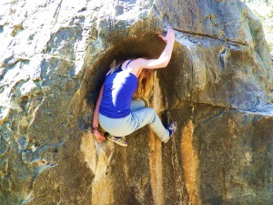 A climber reaches the top of a bouldering route