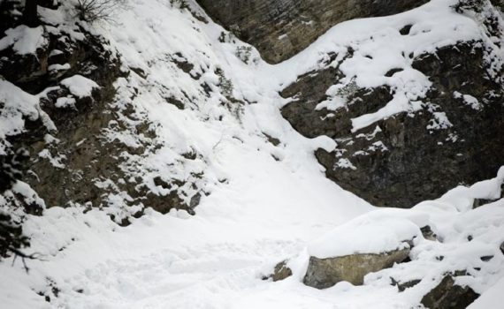 snowshoer walks below snowy rock features
