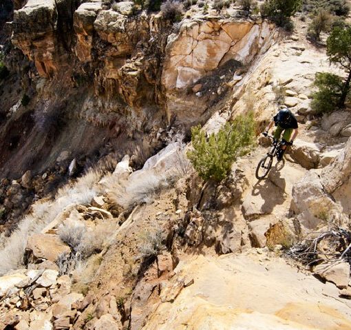 rider mountian bikes along the edge of a rocky cliff on a sunny day