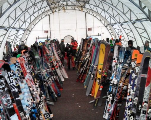 rows of skis standing on end, inside a temporary structure with a round ceiling