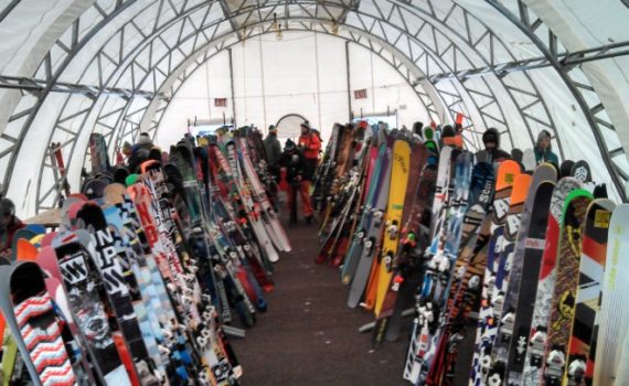 rows of skis standing on end, inside a temporary structure with a round ceiling