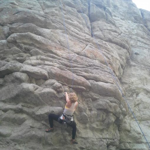 climber at a roof crux on a heavily featured rock wall
