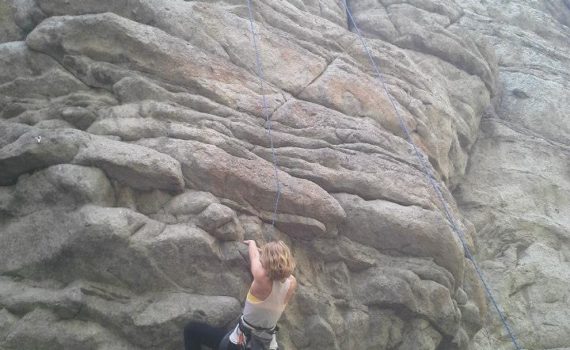 climber at a roof crux on a heavily featured rock wall