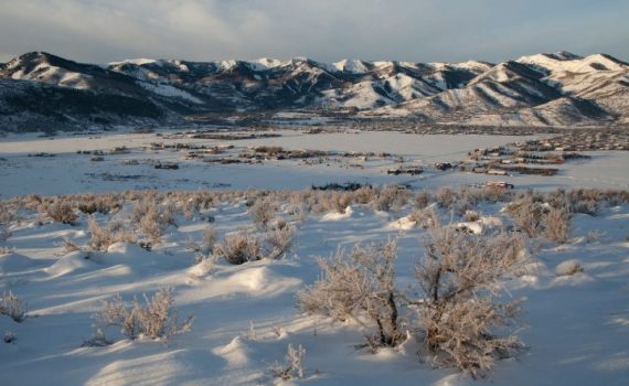 snowy field in the foreground, Wasatch back ski resorts in the distance