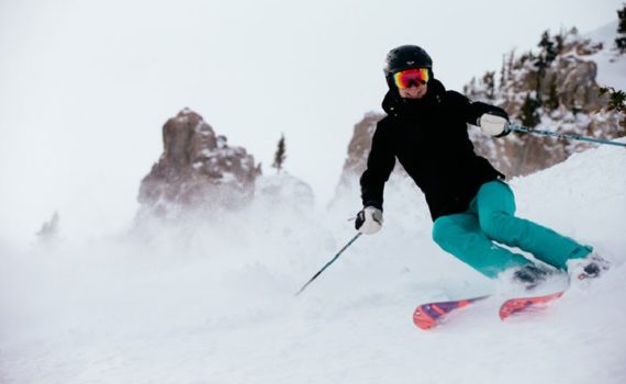 female skier carving a turn with a smile