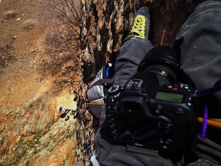 Photographer anchored on rock wall