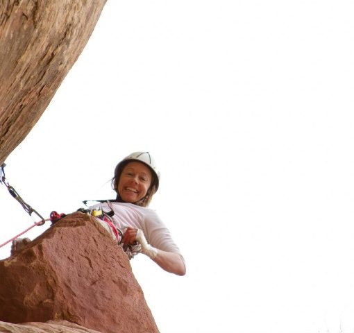 rock climber leading a climb pauses to smile down at the camera