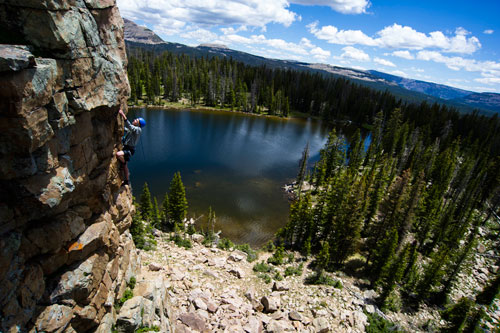A climber on a face with a lake in the background