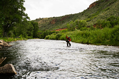 A fisherman fishes in the middle of a river