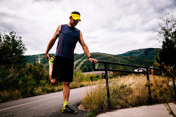 A runner stretches while leaning on a rail