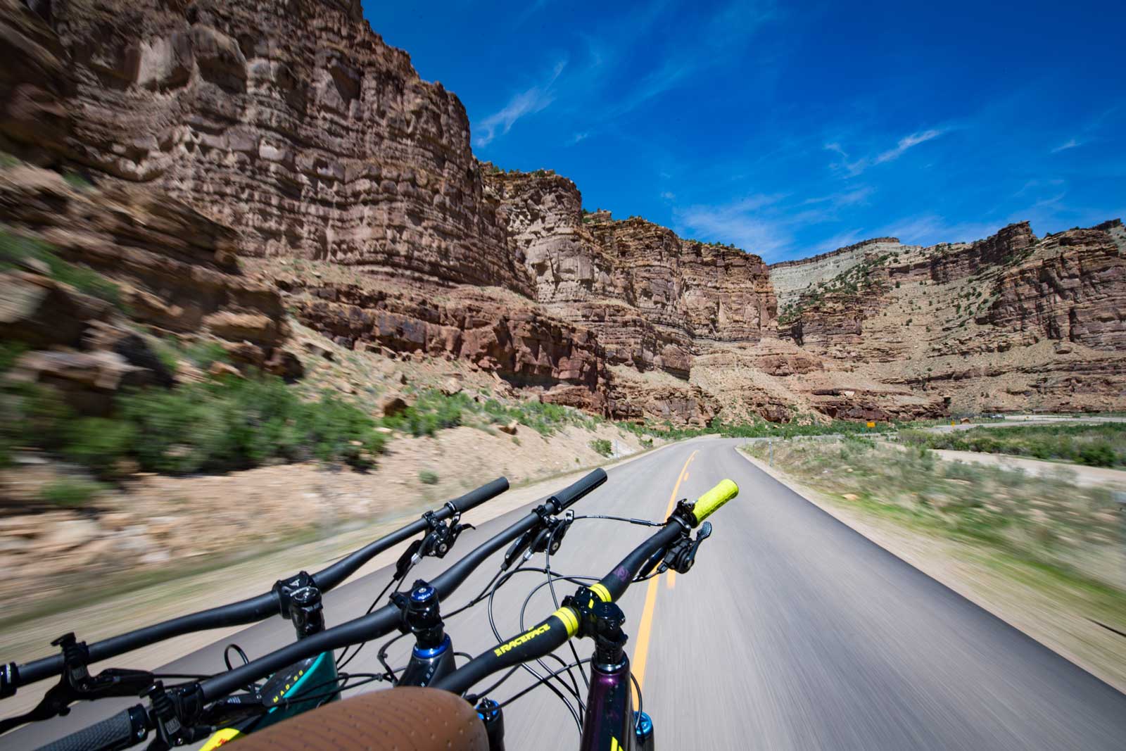 Three bikes in the back of a truck traveling on a road in the Utah desert
