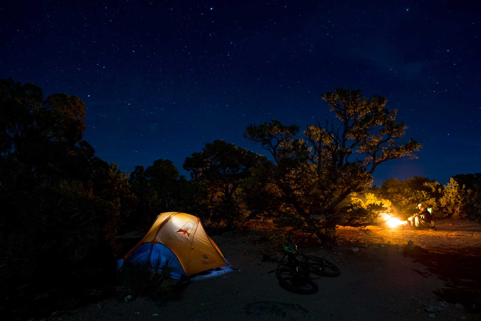 A tent and campfire at night in the Utah desert
