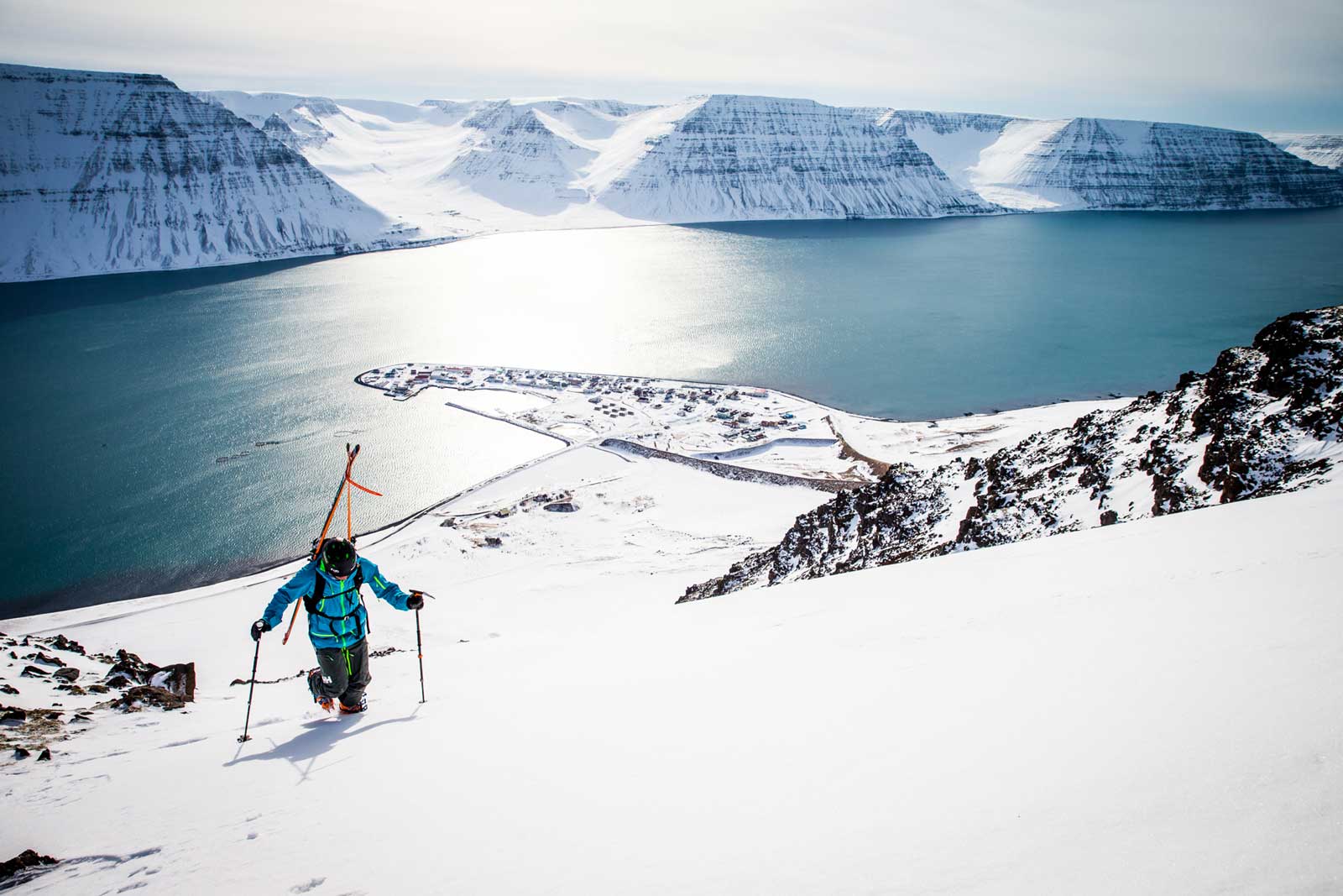 Skier treks uphill with ocean in the background