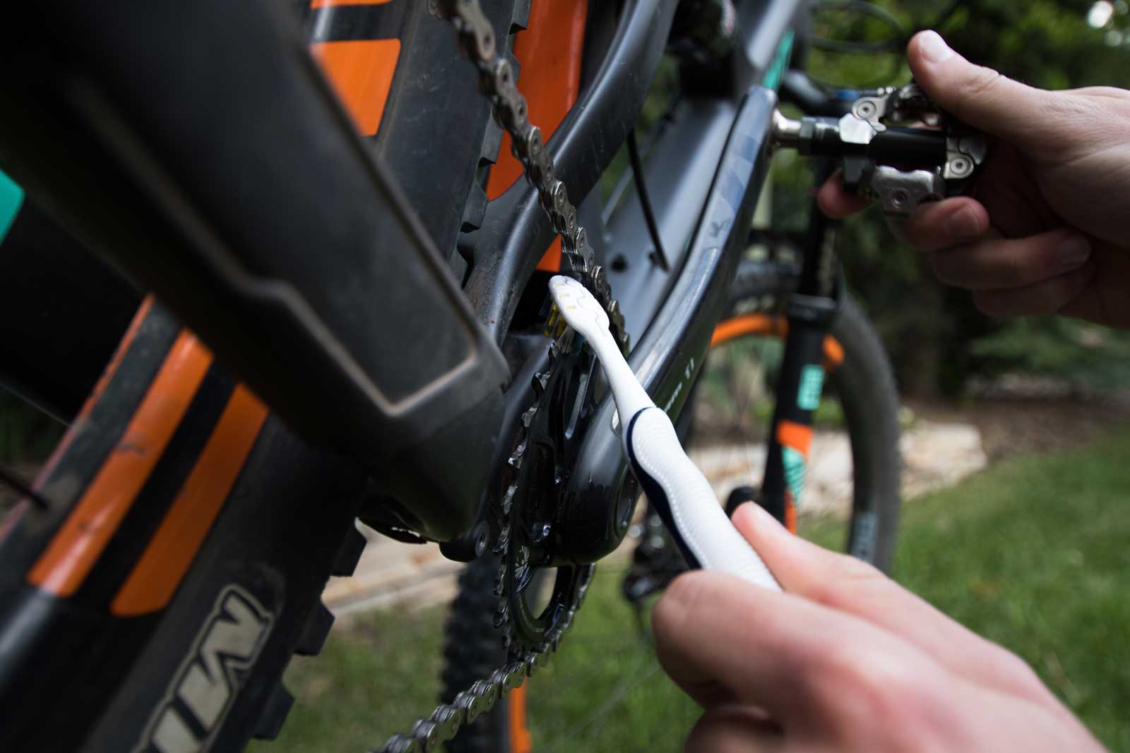 A toothbrush cleaning the front chain ring of a bicycle
