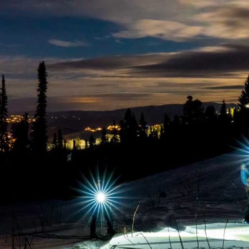 Two skiers skin uphill by headlamp at Park City Mountain Resort