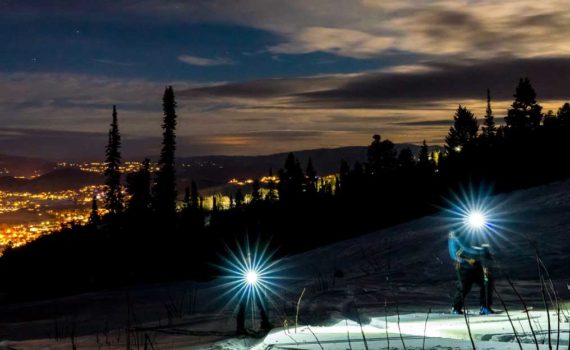 Two skiers skin uphill by headlamp at Park City Mountain Resort