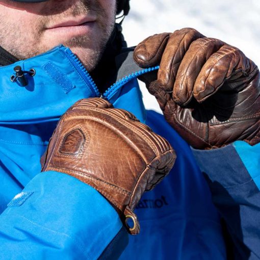 Closeup of skier zipping blue jacket with the Hestra Fall Line ski gloves