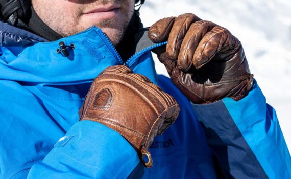 Closeup of skier zipping blue jacket with the Hestra Fall Line ski gloves