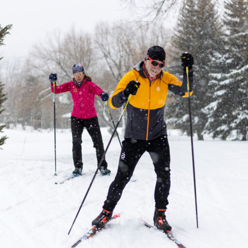 Two Nordic skiers skiing through snowfall near the White Pine Touring Center in Park City, UT