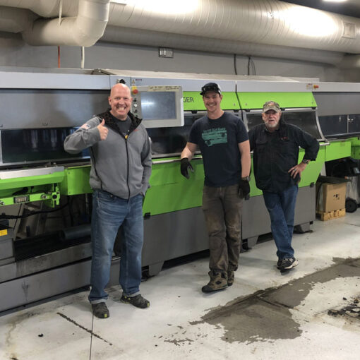 Three technicians stand in front of the new Jupiter tuning machine at Rennstall in Park City, UT