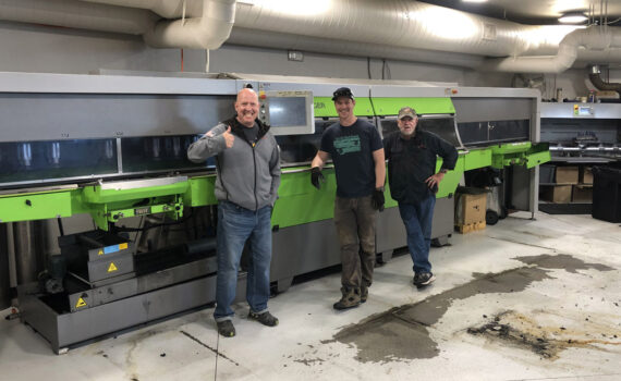 Three technicians stand in front of the new Jupiter tuning machine at Rennstall in Park City, UT