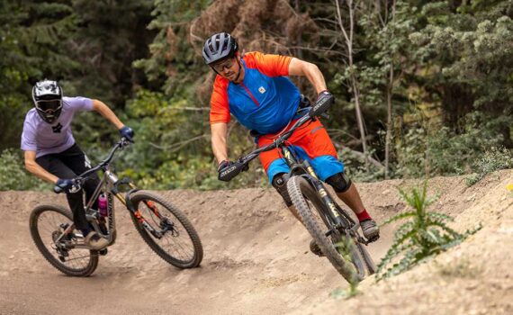 Jans experts race at Deer Valley, one is wearing a red and blue bike kit, the other is wearing a full faced helmet.