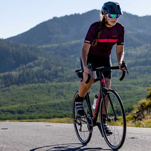 JANS expert riding a sleek road bike, leaning forward in an aerodynamic position with determination on a smooth road.