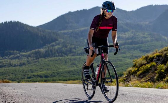 JANS expert riding a sleek road bike, leaning forward in an aerodynamic position with determination on a smooth road.