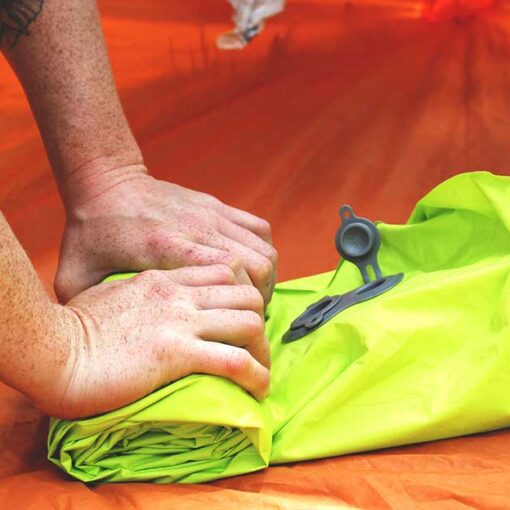 Jans Expert rolls up an inflatable sleeping pad to secure onto her backpack.