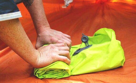 Jans Expert rolls up an inflatable sleeping pad to secure onto her backpack.