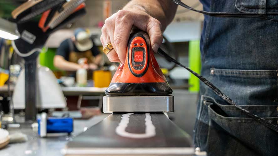 A Jans Expert applies a fresh coat of hot wax on a ski base. 