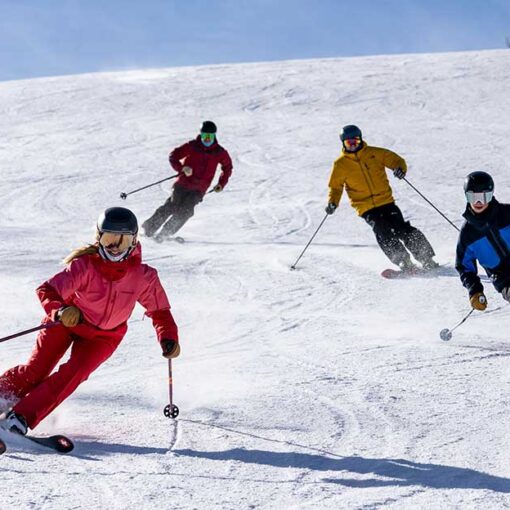 Four expert skiers from the Jans team skiing on a groomed run during a blue-sky day at Deer Valley Resort, Park City, UT