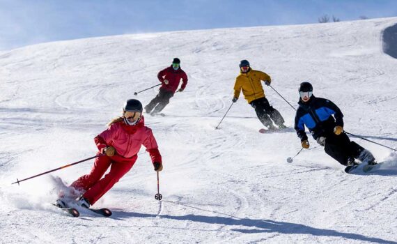 Four expert skiers from the Jans team skiing on a groomed run during a blue-sky day at Deer Valley Resort, Park City, UT