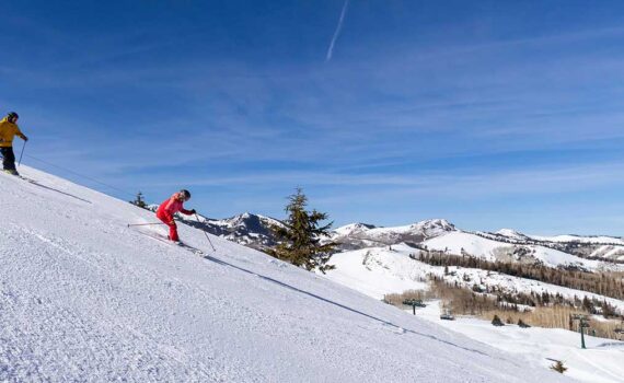 Skiers cruise down freshly groomed snow at Deer Valley Resort on a bluebird day
