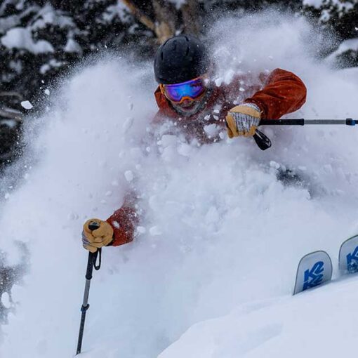 Jans Expert skiing through trees in deep powder snow, kicking up plumes of fresh snow above the head while skiing at Solitude Resort, Utah.