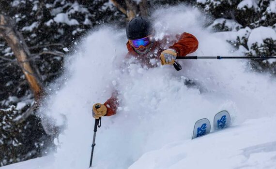 Jans Expert skiing through trees in deep powder snow, kicking up plumes of fresh snow above the head while skiing at Solitude Resort, Utah.