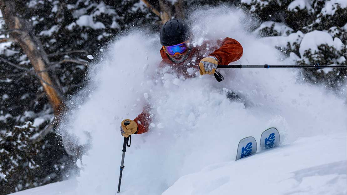 Jans Expert skiing through trees in deep powder snow, kicking up plumes of fresh snow above the head while skiing at Solitude Resort, Utah.